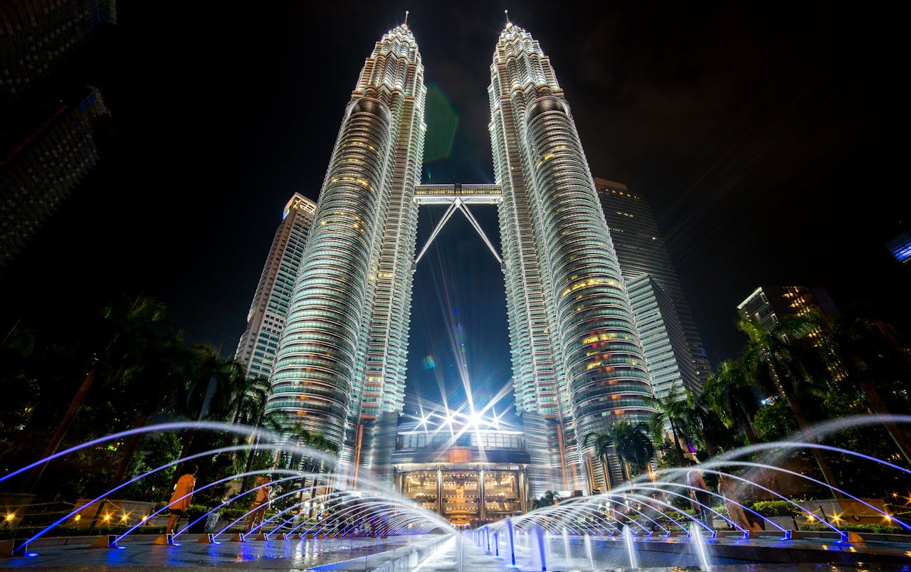 Services Stunning night view of the illuminated Petronas Twin Towers in Kuala Lumpur with fountains in the foreground.